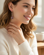 Amelia Jane Handmade Creations ametrine drop earrings with S925 silver posts worn by a smiling woman in a white sweater