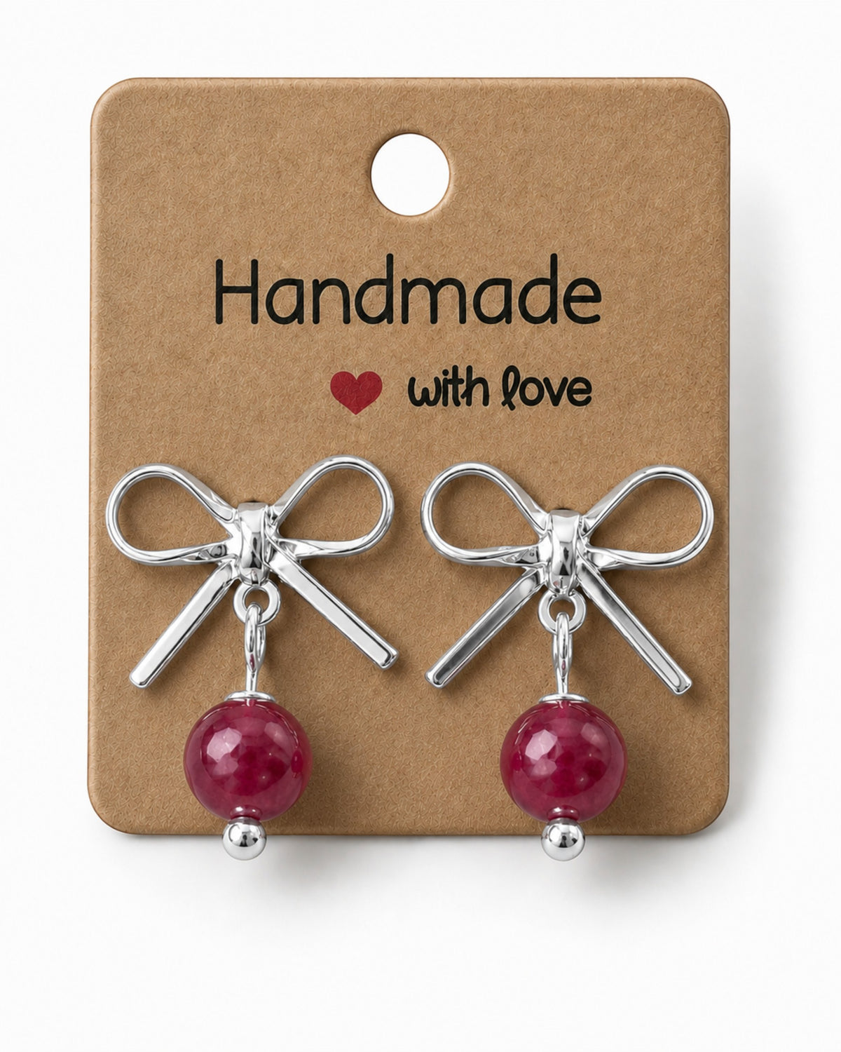 Amelia Jane Handmade Creations platinum plated bow stud earrings with dangling red beads on a display card