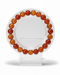 Amelia Jane Handmade Creations 7-inch faceted carnelian bead bracelet on a clear circular display stand.