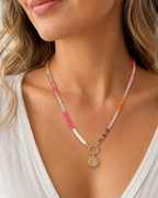 Amelia Jane Handmade Creations gemstone sunburst necklace with colorful beads and gold pendant on a woman