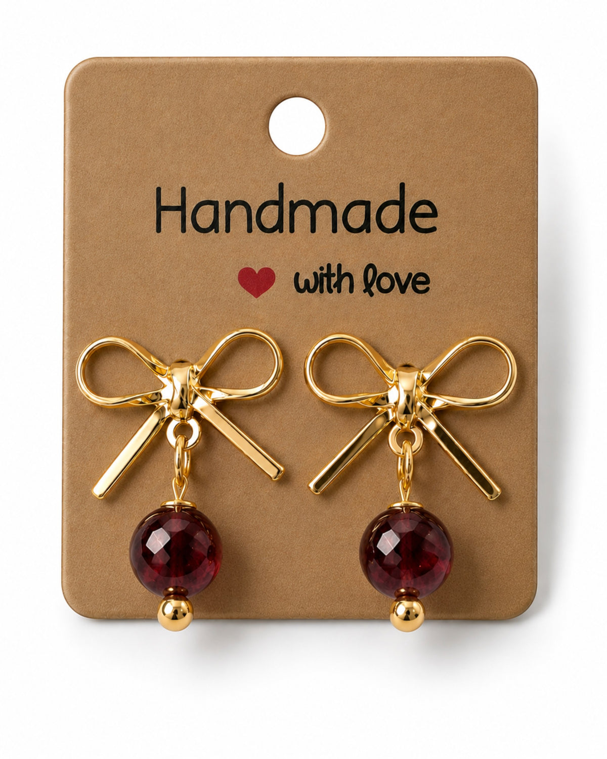 Amelia Jane Handmade Creations gold plated bow stud earrings with dangling dark red faceted beads on display card.