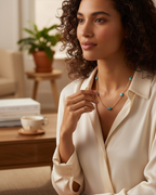 Amelia Jane Handmade Creations Larimar necklace with gold-tone wire wrapping on a model wearing a cream silk blouse.
