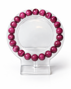 Amelia Jane Handmade Creations 7-inch magenta tiger's eye beaded bracelet on a clear display stand