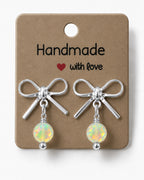 Amelia Jane Handmade Creations platinum plated bow stud earrings with iridescent crystal beads on a display card.