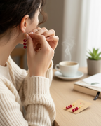 Amelia Jane Handmade Creations ruby dangle earrings with S925 posts worn by a woman at a desk with coffee