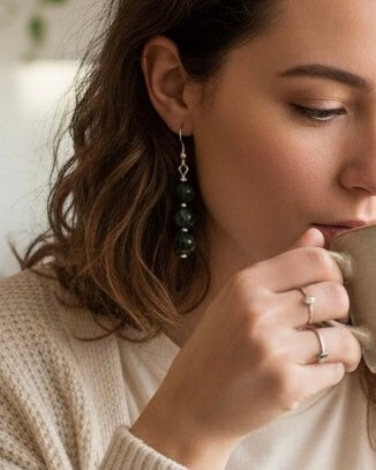 Amelia Jane Handmade Creations seraphinite dangle earrings with S925 silver posts worn by a woman holding a mug