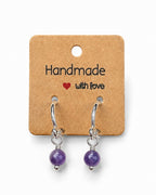 Amelia Jane Handmade Creations 15mm silver-filled huggie hoop earrings featuring dangling purple amethyst gemstones.