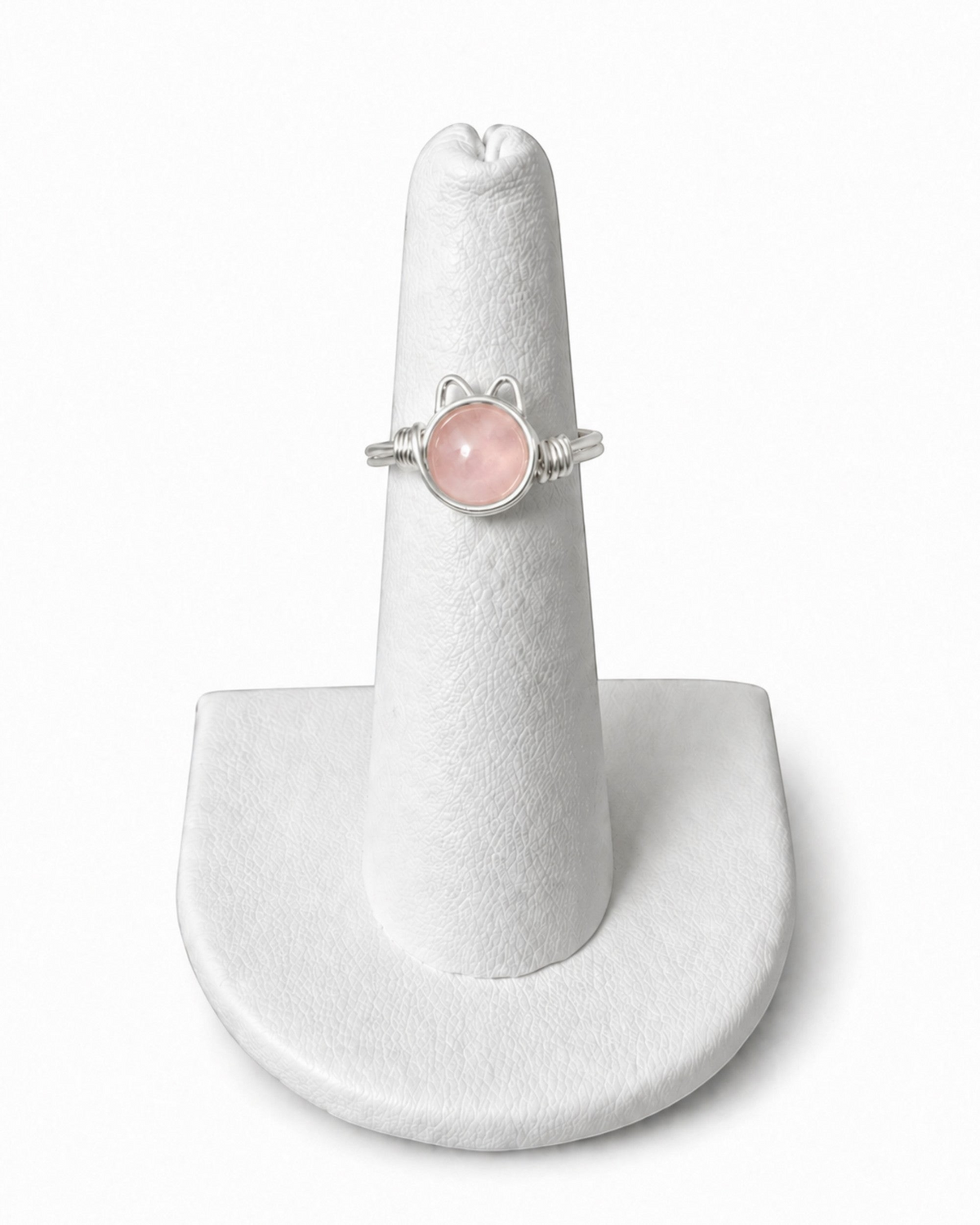 Amelia Jane Handmade Creations wire wrapped kitty ring with a round pink stone and silver wire on a display stand