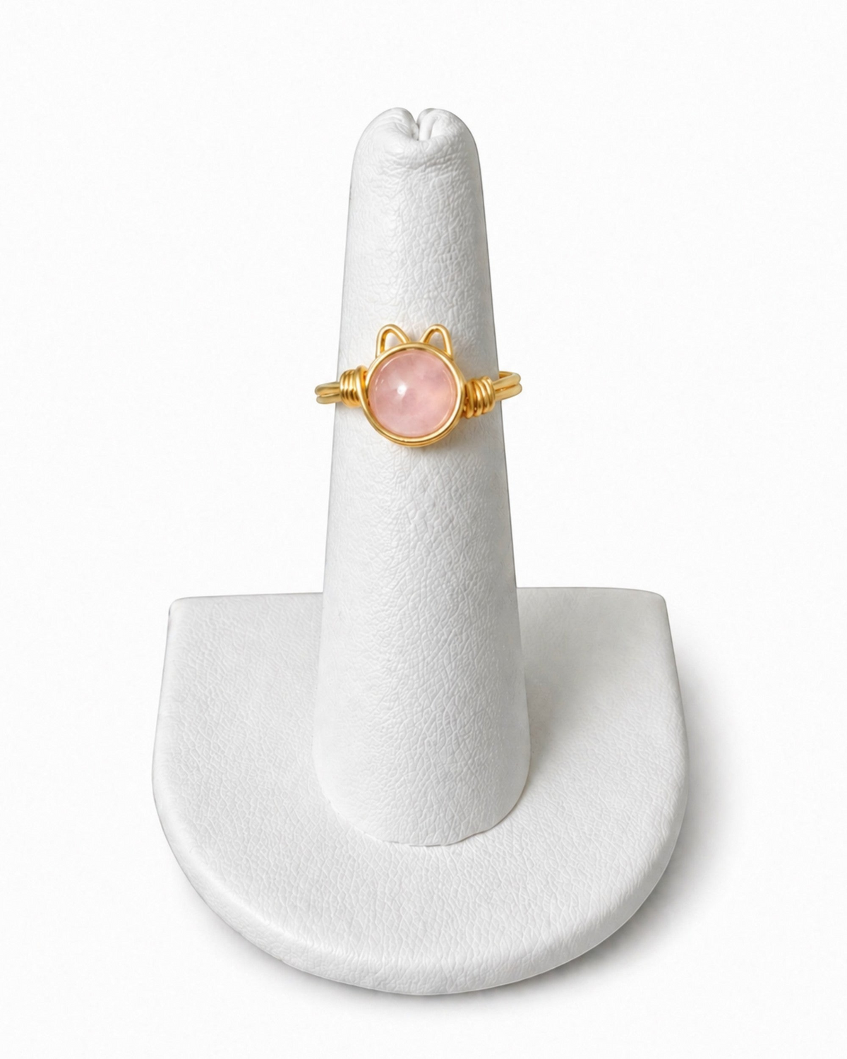 Amelia Jane Handmade Creations wire wrapped kitty ring with a round pink gemstone set in gold wire on a ring stand.